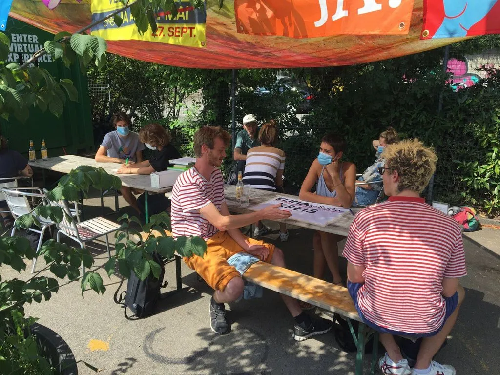 Eine Gruppe von Menschen sitzt draussen an einem Tisch.