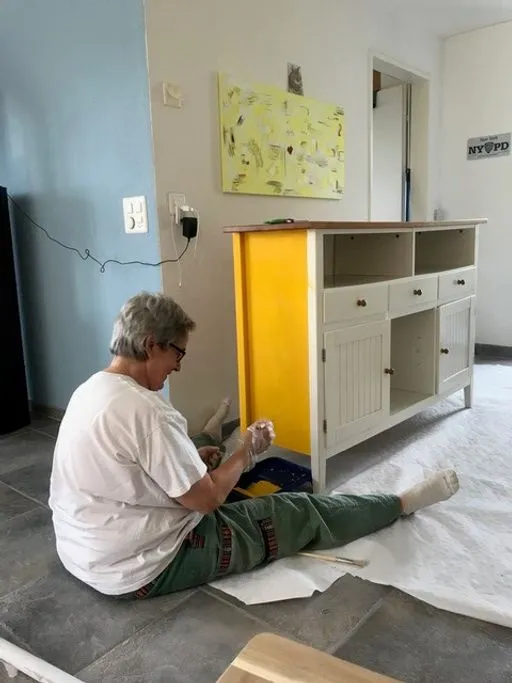 Storyteller streicht einen Schrank in gelber Farbe.