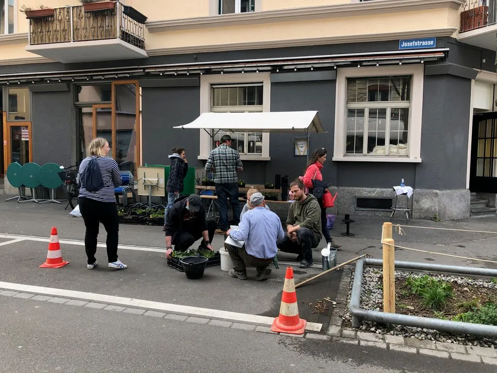 Eine kleine Gruppe bespricht sich neben einer Baumrabatte.
