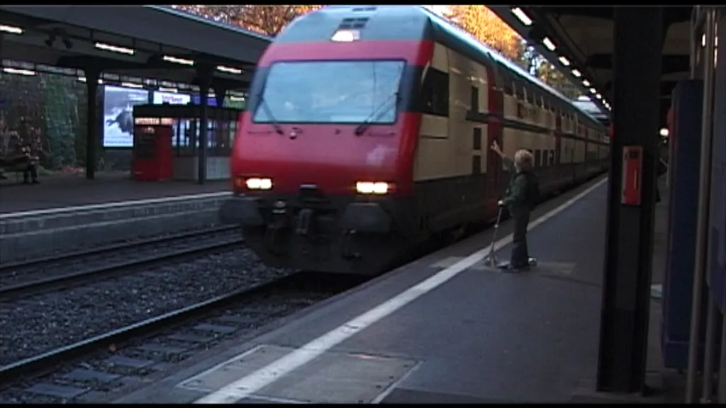 ein Junge mit Trottinett winkt dem Lokführer