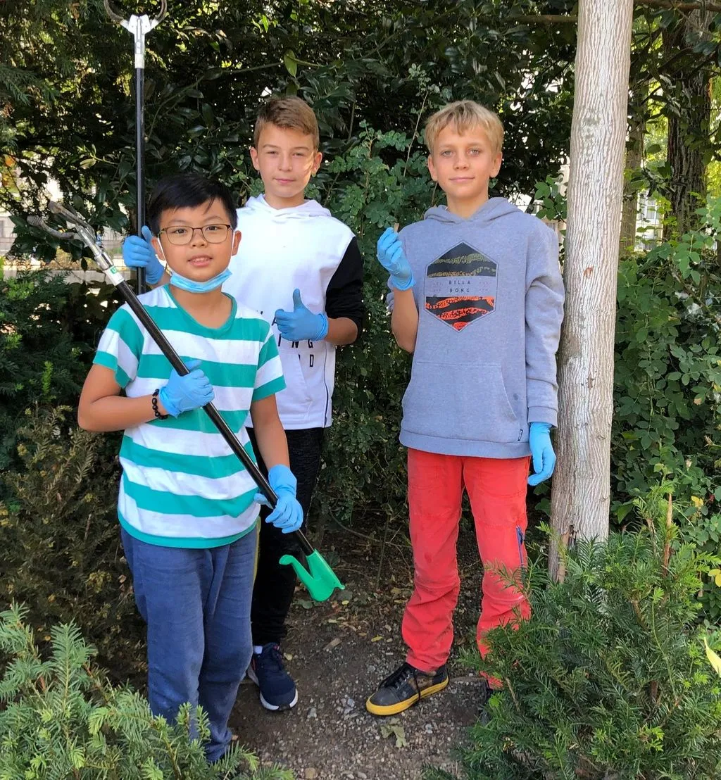 Drei Kinder sammeln Müll.