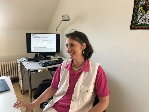 Person sitzt vor Computer mit wissenschaftlicher Grafik auf dem Bildschirm.