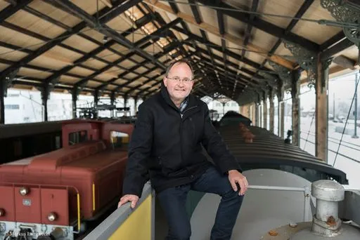 Mann sitzt auf alter Lokomotive.