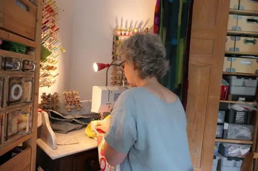 Storyteller arbeitet an der Nähmaschine, umgeben von gut sortierten Fäden und anderen Nähmaterialien. 
