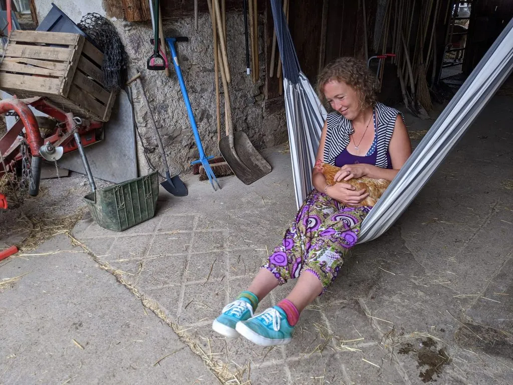 Storyteller sitzt in einer Hängematte mit einem Huhn im Schoss.