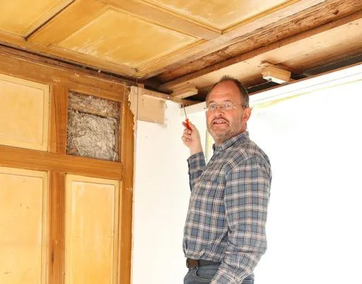 Mann renoviert alte Holzdecke.