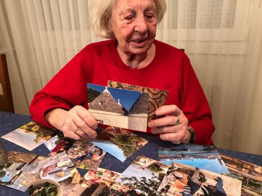 Ältere Frau schaut einen Stapel an alten Postkarten durch