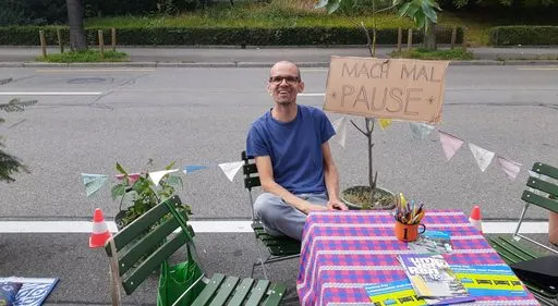 Mann sitzt auf Stuhl auf Parkplatz.