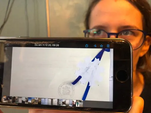 Storyteller zeigt ein offizielles Dokument mit amtlichem Stempel auf dem Smartphone.